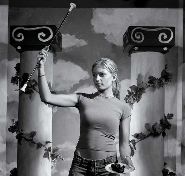 A prom queen bearing a twriling baton and a slice of pie